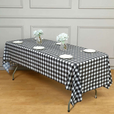 Black and white checkered tablecloth on a wooden table with plates and vases.