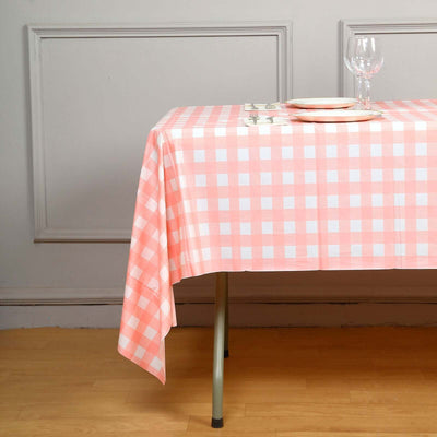 Pink checkered tablecloth draped over a table with plates and glasses.