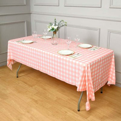 Pink gingham tablecloth draped over a dining table set with plates and glasses.
