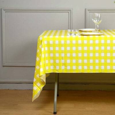 Yellow checkered tablecloth draped over a table with plates and glassware.