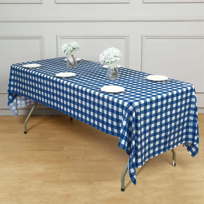 Blue and white checkered tablecloth on a table with floral centerpieces and plates.