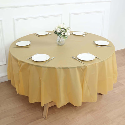 Round yellow tablecloth on a dining table set with plates and cutlery.