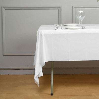 White tablecloth draped elegantly over a table with dinnerware and glassware.