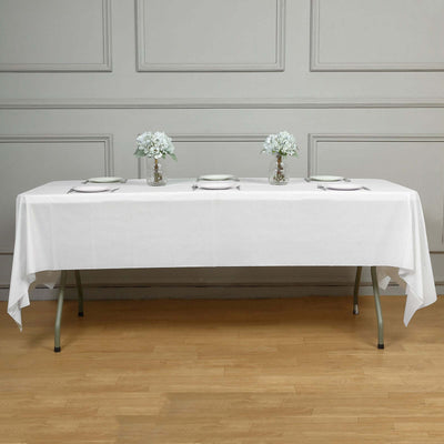 Elegant white table setup with flowers and dinnerware.