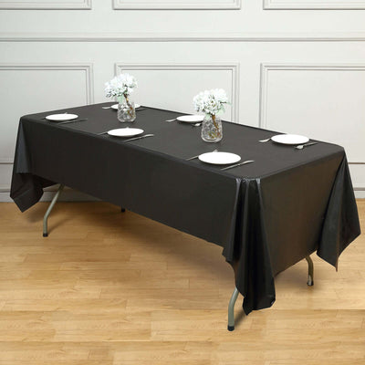 Black tablecloth draped over a table set for dining with white plates and floral centerpieces.
