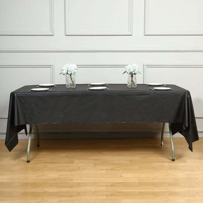Black tablecloth draped over a long table with white flowers in vases.