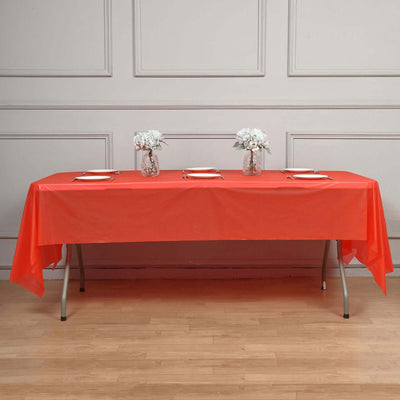 Red tablecloth draped over a long table set with plates and floral centerpieces.