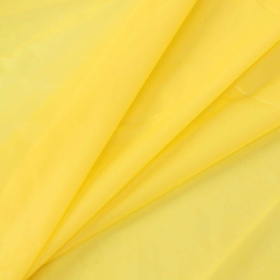 Yellow fabric draped in folds on a plain background.