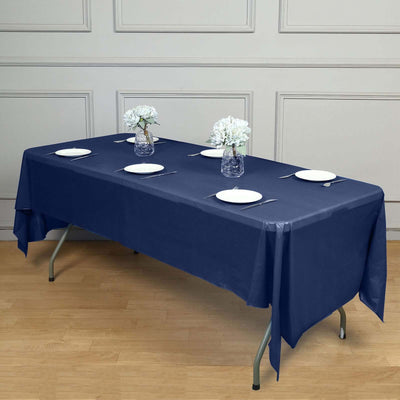 Navy blue tablecloth on a dining table with plates and flower vases.
