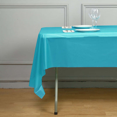 Turquoise tablecloth draped over a table with plates and glasses.