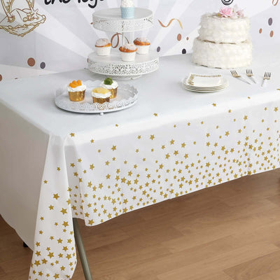 Gold star tablecloth on a decorated table with desserts and cake.
