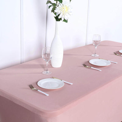 Elegant pink tablecloth set for dining with glassware and plates.