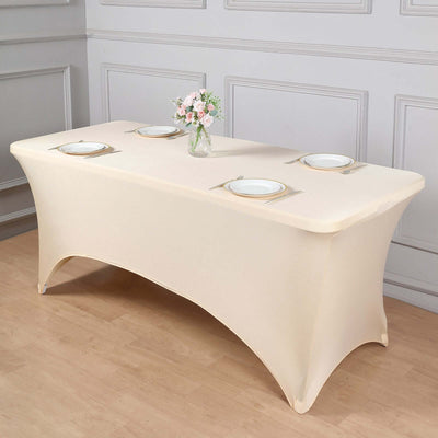 Beige table cover draped over rectangular table with plates and vase of flowers.