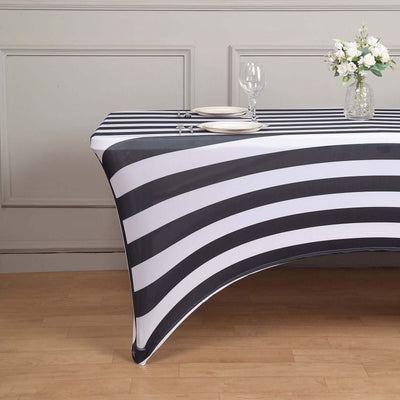 Black and white striped table cover on a wooden table with glassware and flowers.