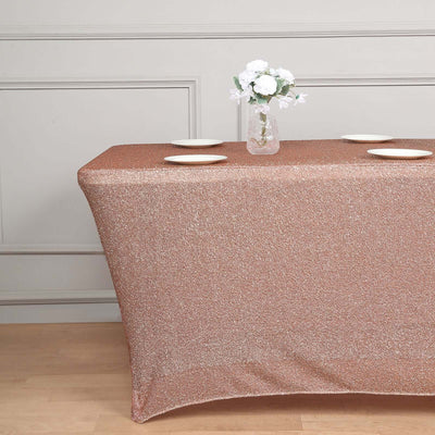 Rose gold glitter tablecloth draped over a table with plates and flowers.