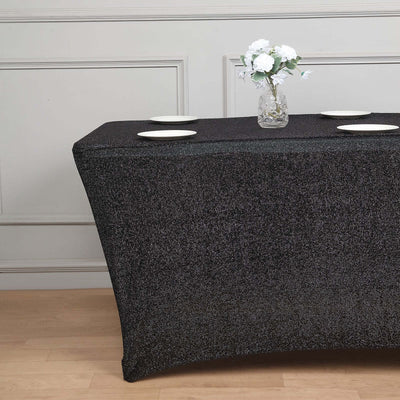 Black tablecloth draped over a table with white plates and a floral centerpiece.