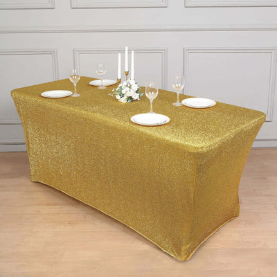 Gold glitter tablecloth on a banquet table set with plates and glasses.