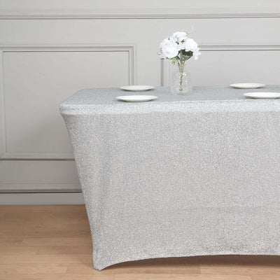 Silver glitter tablecloth draped over a table with plates and a vase of flowers.