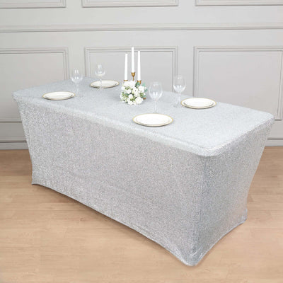 Silver glitter table cover with plates and glasses set for dining.