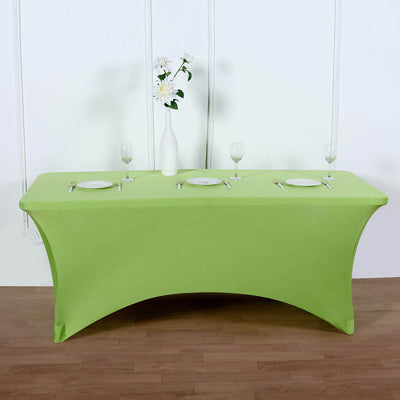 Green table cover draped over a table set for dining with plates and glasses.
