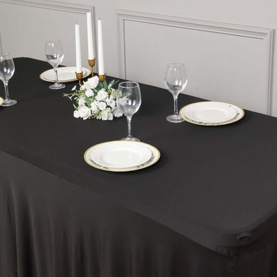 Elegant black tablecloth set for formal dining with glassware and floral centerpiece.