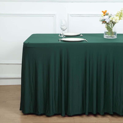 Green tablecloth draping over a table set with plates and flowers.