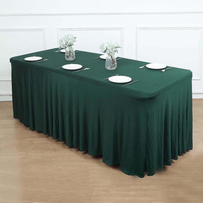 Green tablecloth draped over a long table set with plates and vases.