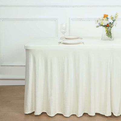 White tablecloth draped over a table with plates and a vase of flowers.