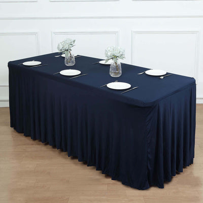 Navy tablecloth draped over a table set for dining with plates and flowers.