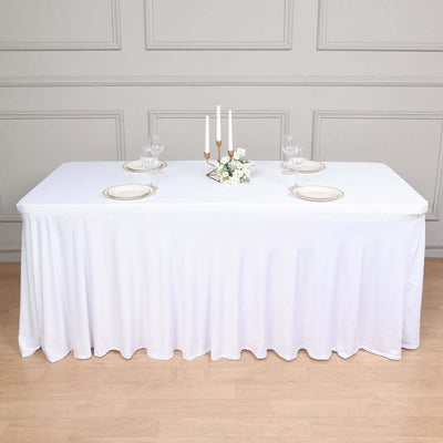 Elegant white tablecloth draped over a banquet table with set plates and candles.