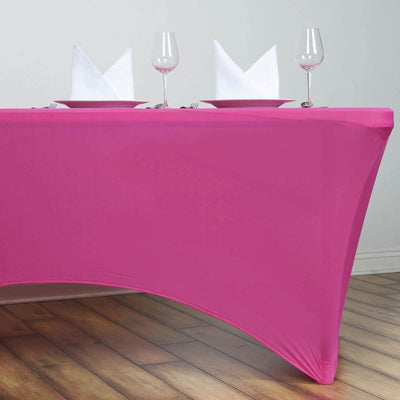 Pink table cover draped over a table with plates and glasses set for dining.