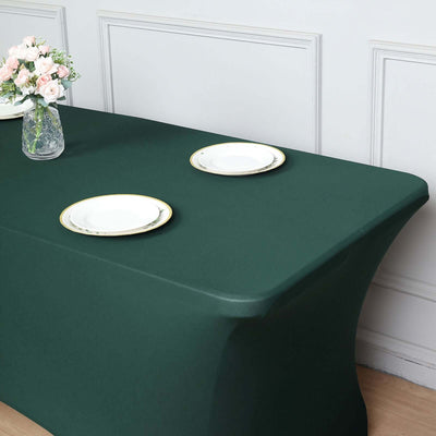 Green fitted table cover with white plates on a dining table.