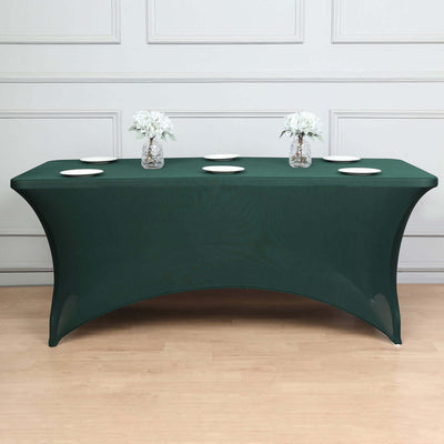 Green stretch table cover with decorative flowers and plates on a table.