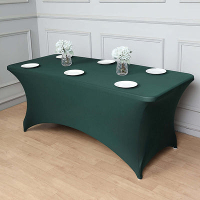 Green table cover with plates and vases arranged on a styled table setting.