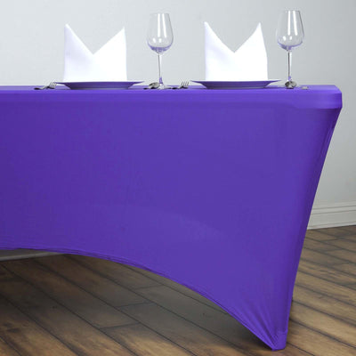 Purple tablecloth draped over a table set for dining with glasses and folded napkins.