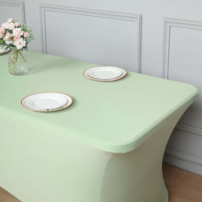 Mint green table with white plates and a vase of flowers.