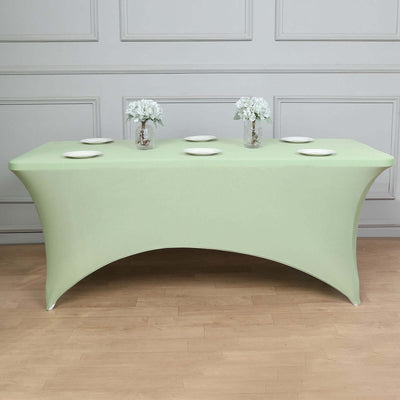 Green fitted table cover with white plates and floral centerpieces.