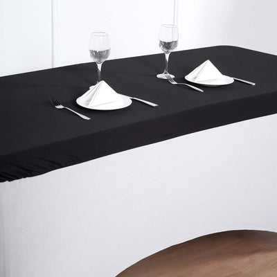 Black table cover set on a two-tone table with dining setup and glassware.