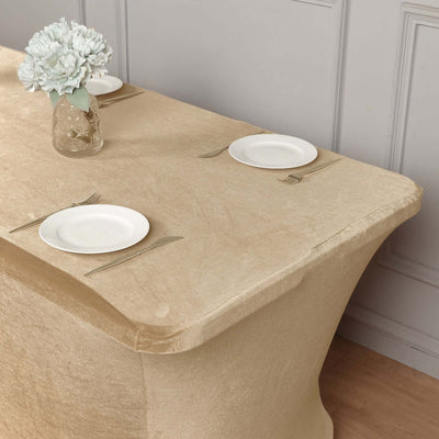 Beige tablecloth draped over a table with plates and a vase of flowers.