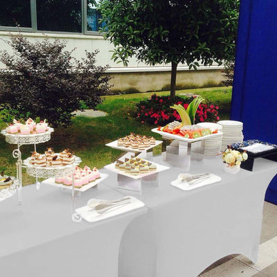 Dessert table with assorted cakes, pastries, and fruits at an outdoor event.