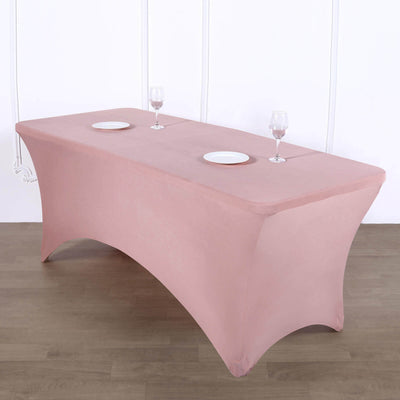 Pink table cover draped over a rectangular table with plates and glasses.