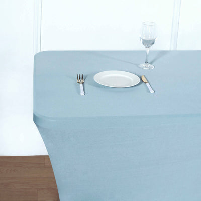 Blue tablecloth draped over a table set with a plate and glass.