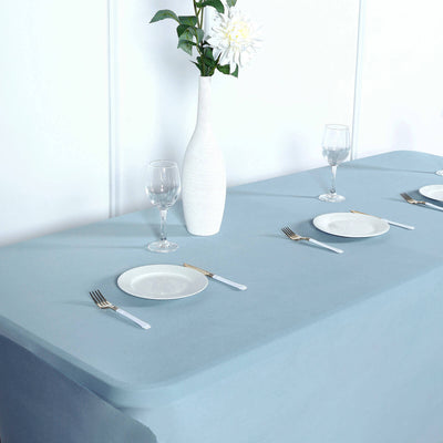 Elegant blue tablecloth set with plates, glasses, and vase.