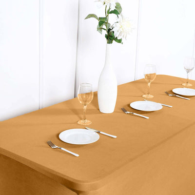 Elegant table setting with a mustard tablecloth, plates, glasses, and a vase of flowers.