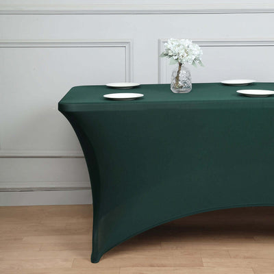 Green table cover with plates and flower vase in a staged setting.