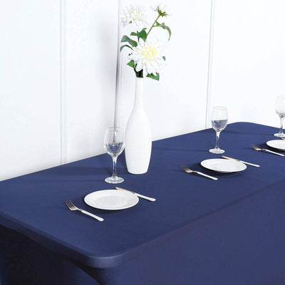 Elegant dining setup with a navy tablecloth, plates, and flowers in a vase.