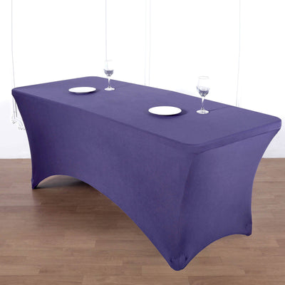 Purple stretch table cover on a wooden surface with plates and glasses.