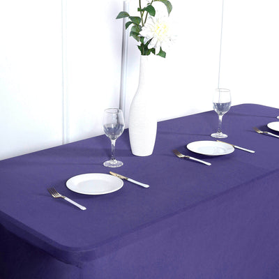 Purple tablecloth with white plates and glassware on a dining table.