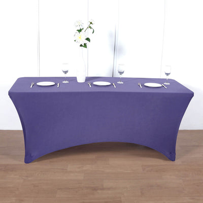 Purple table cover draped over a rectangular table with plates and glasses set.