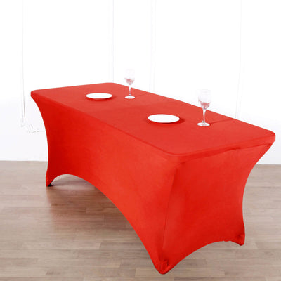 Red stretch table cover with plates and glasses on a wooden floor.